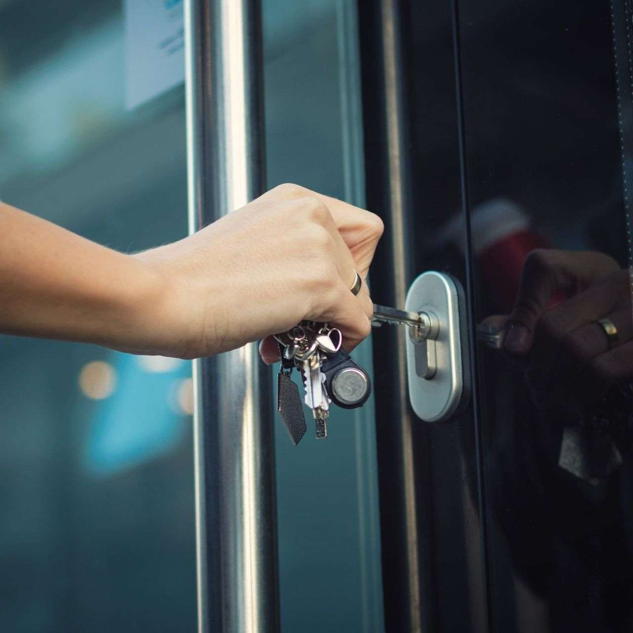 Person unlocking a door with keys.