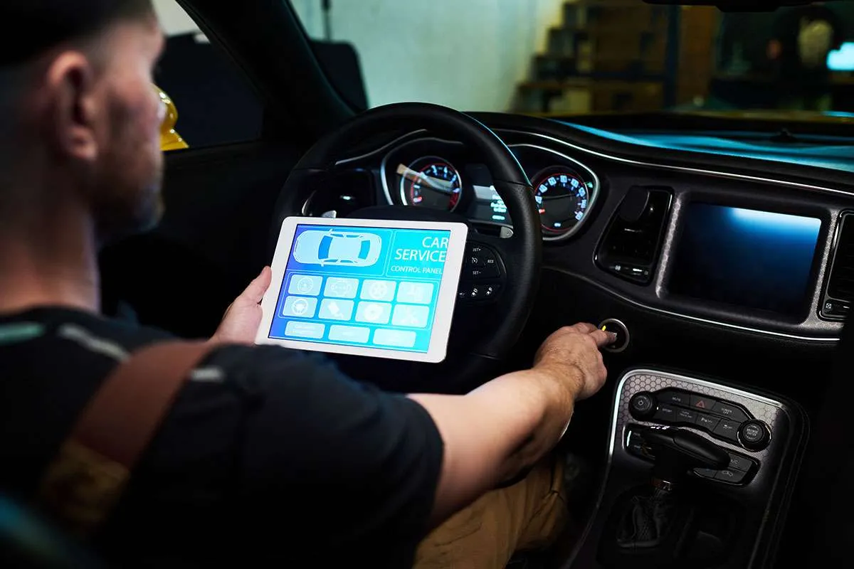 Man using digital car diagnostic tool while driving.